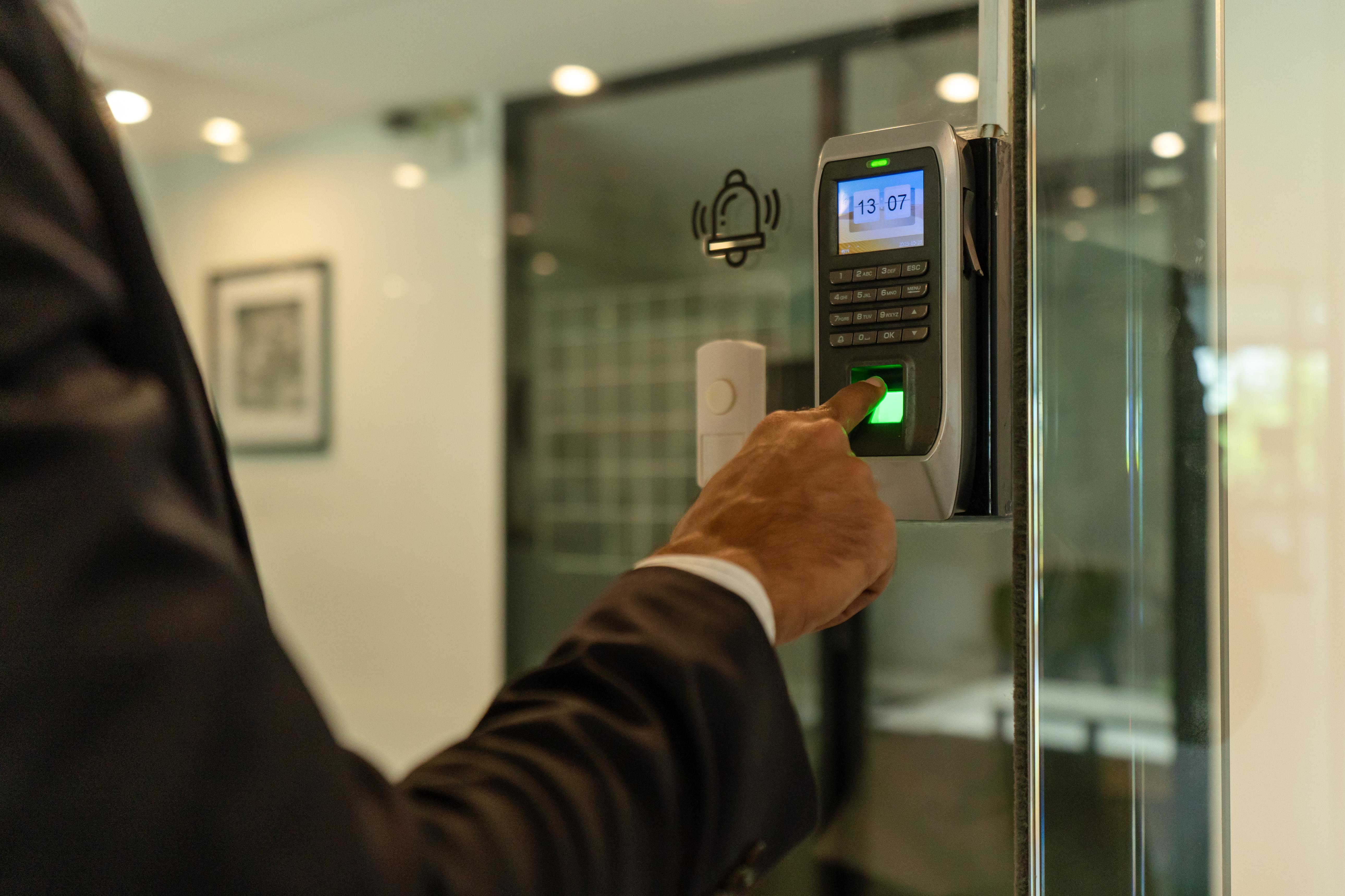 Employee scanning a fingerprint on a biometric attendance device at the office entrance